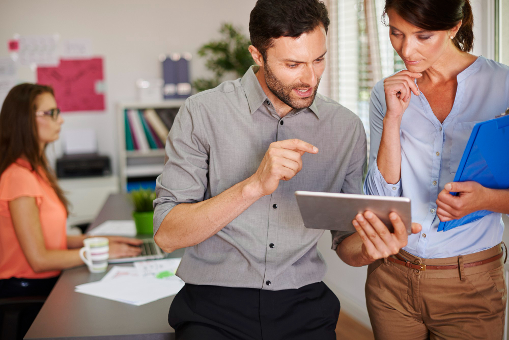 Profesionales analizando una evaluación de desempeño laboral en tablet. Enfocados en feedback y corrección de errores.